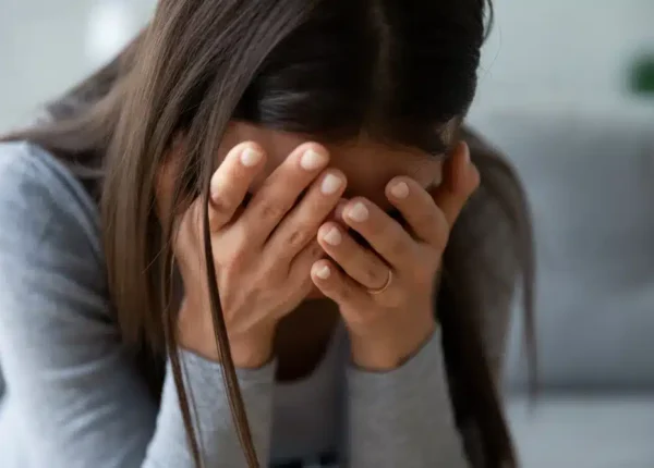 Crying woman with her head in her hands and a wedding ring