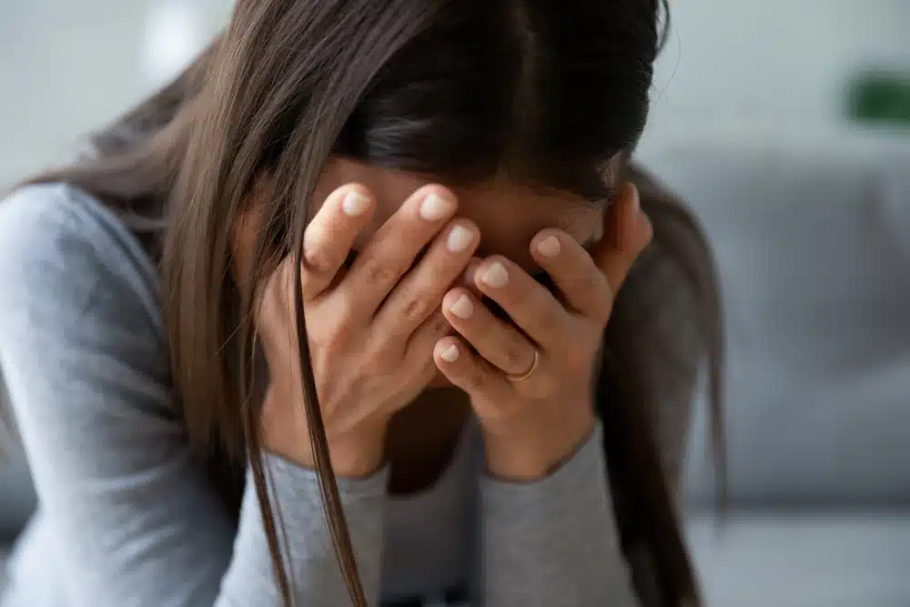 Crying woman with her head in her hands and a wedding ring