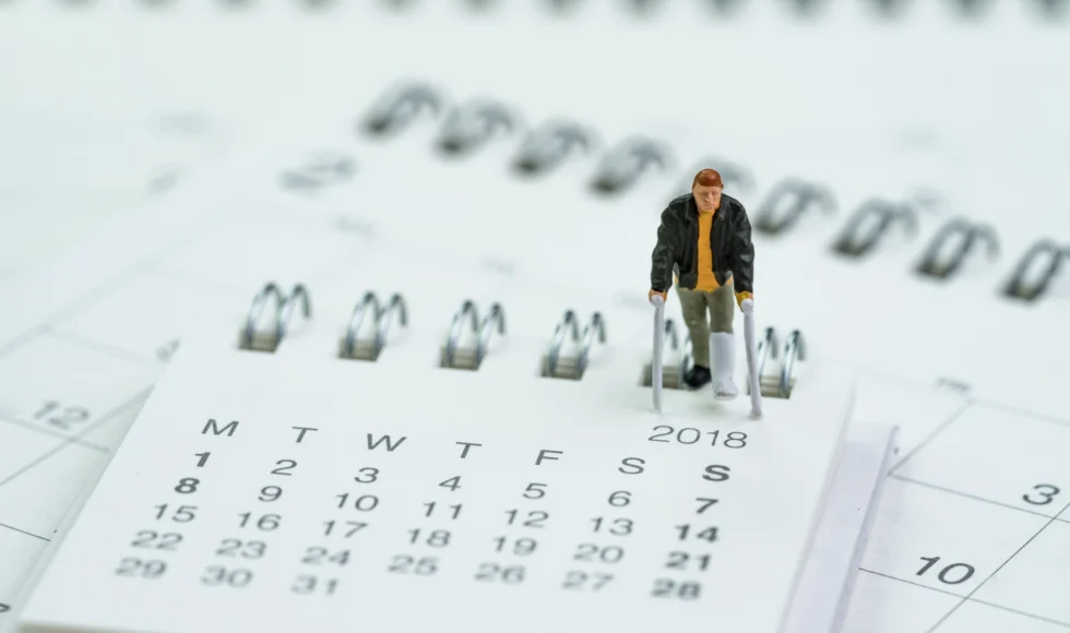 small figurine of a man on crutches walking on a calendar