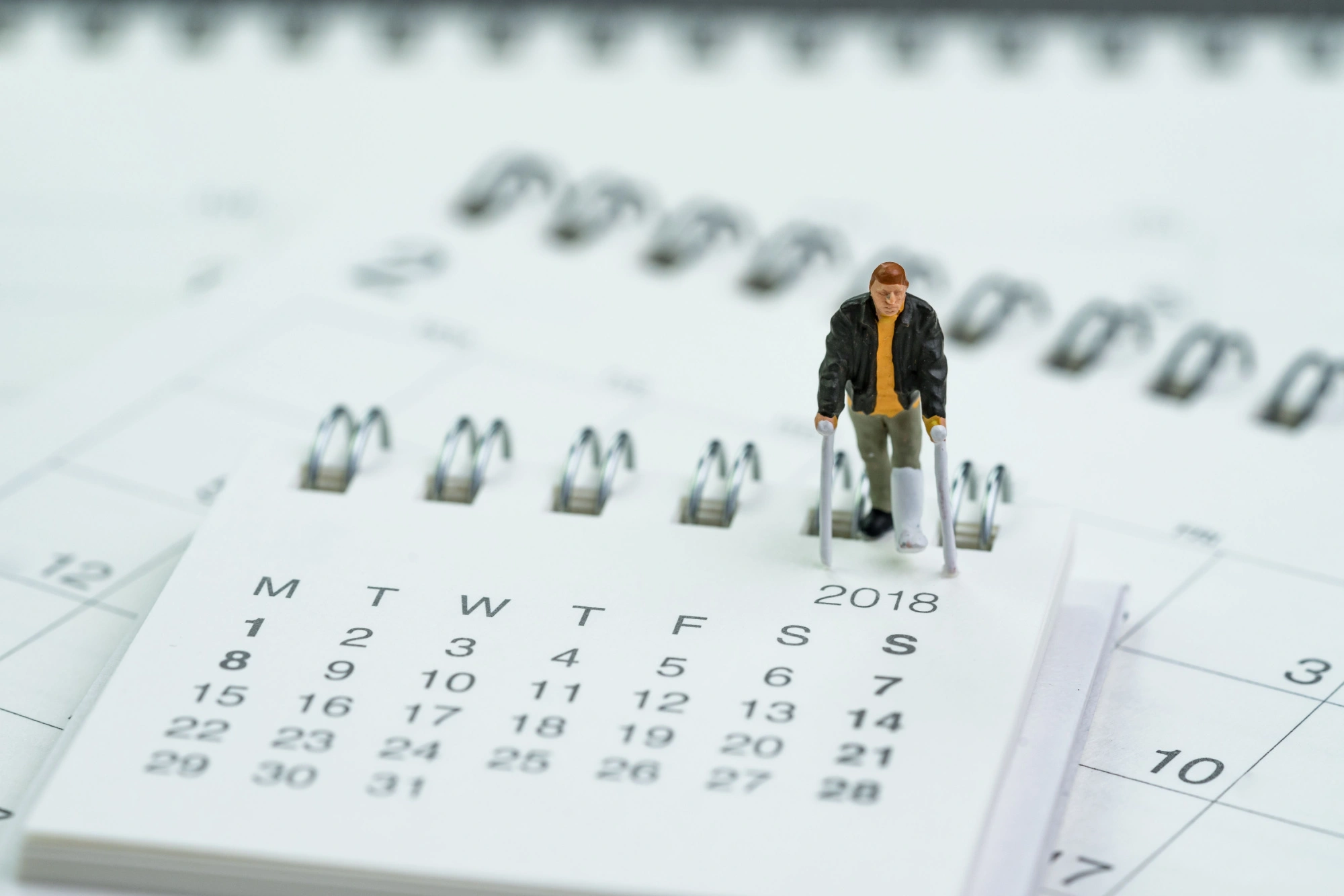 small figurine of a man on crutches walking on a calendar