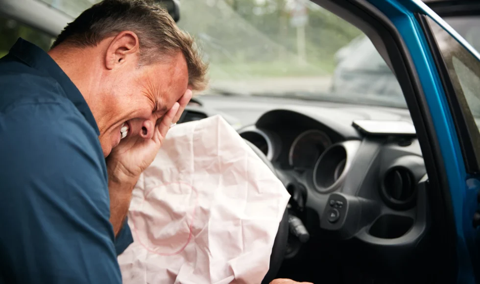 Can you sue for airbag injuries? Photo of man in pain hit by airbag.