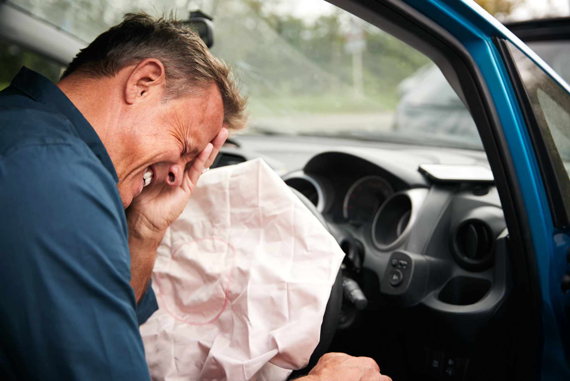 Can you sue for airbag injuries? Photo of man in pain hit by airbag.