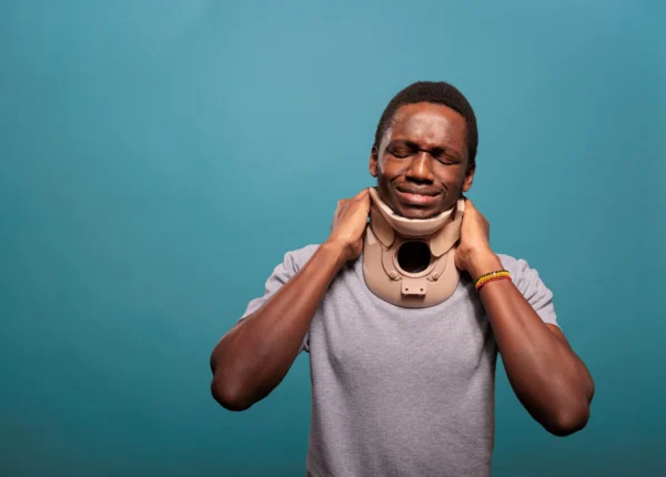 Injured man in a neck brace holding his neck in discomfort