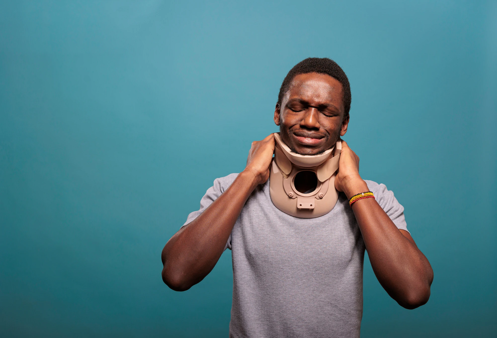 Injured man in a neck brace holding his neck in discomfort