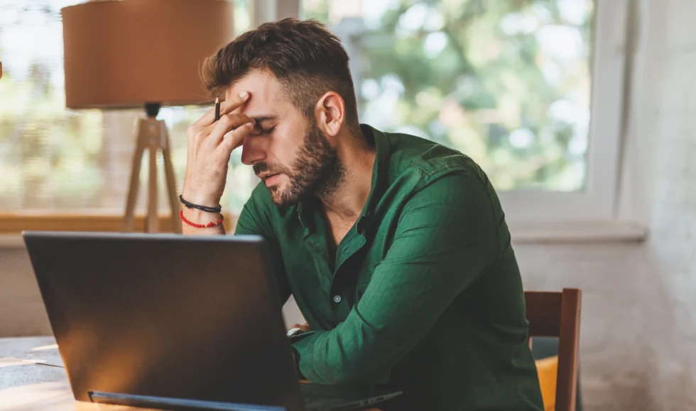 Frustrated young man sitting at laptop