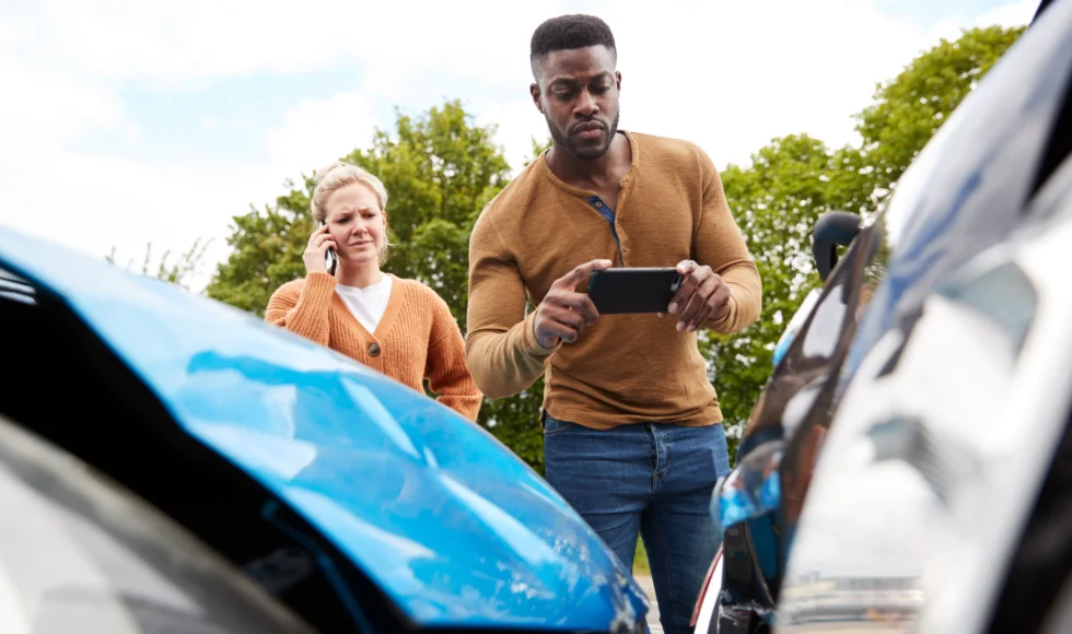 Man taking a photo of a car wreck