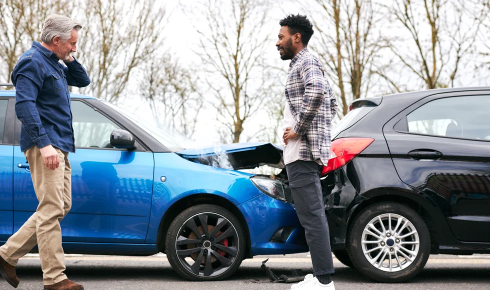 Two drivers look at their cars after a rear-end accident.