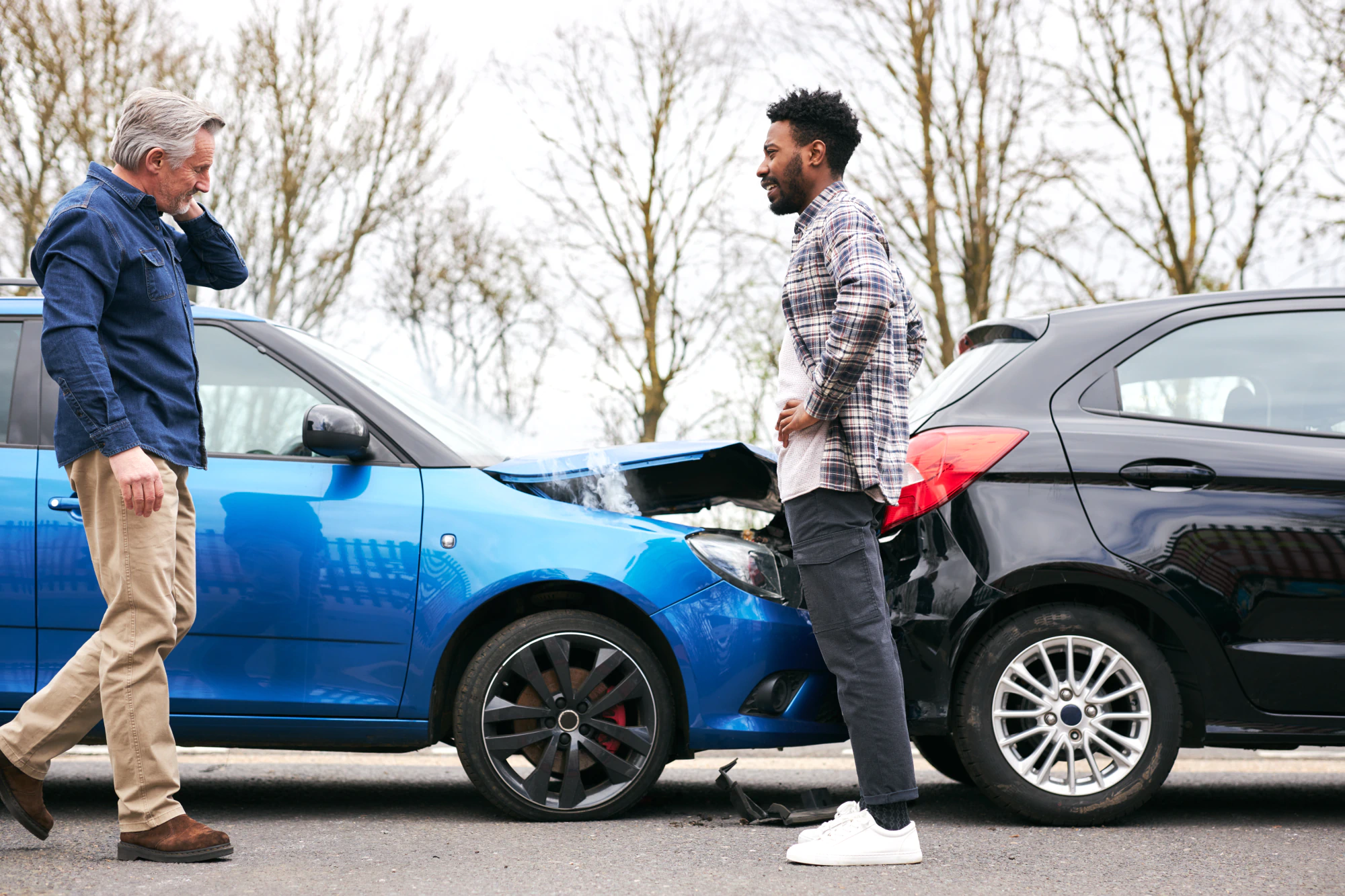 Two drivers look at their cars after a rear-end accident.