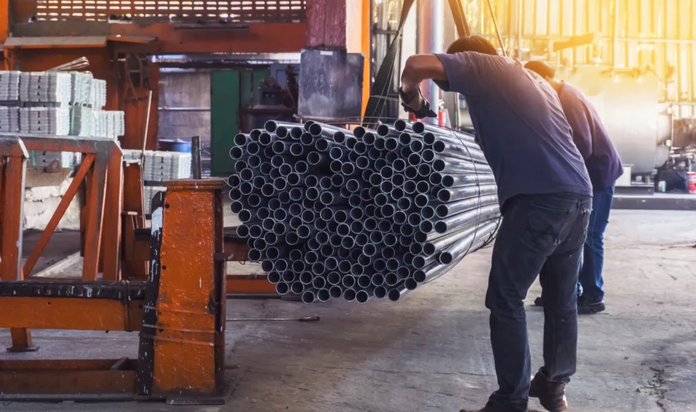 Men at working lifting hundreds of metal pipes.