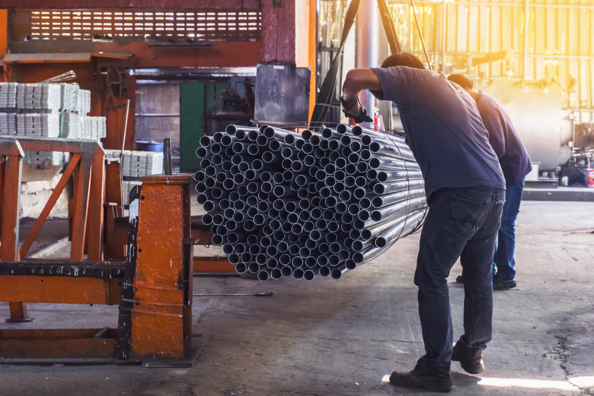 Men at working lifting hundreds of metal pipes.