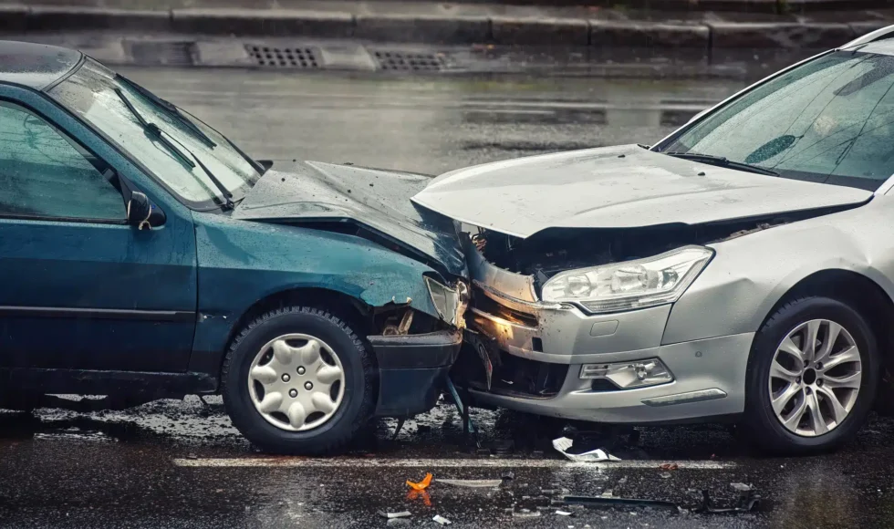 Two cars involved in a head-on collision on a rainy street.