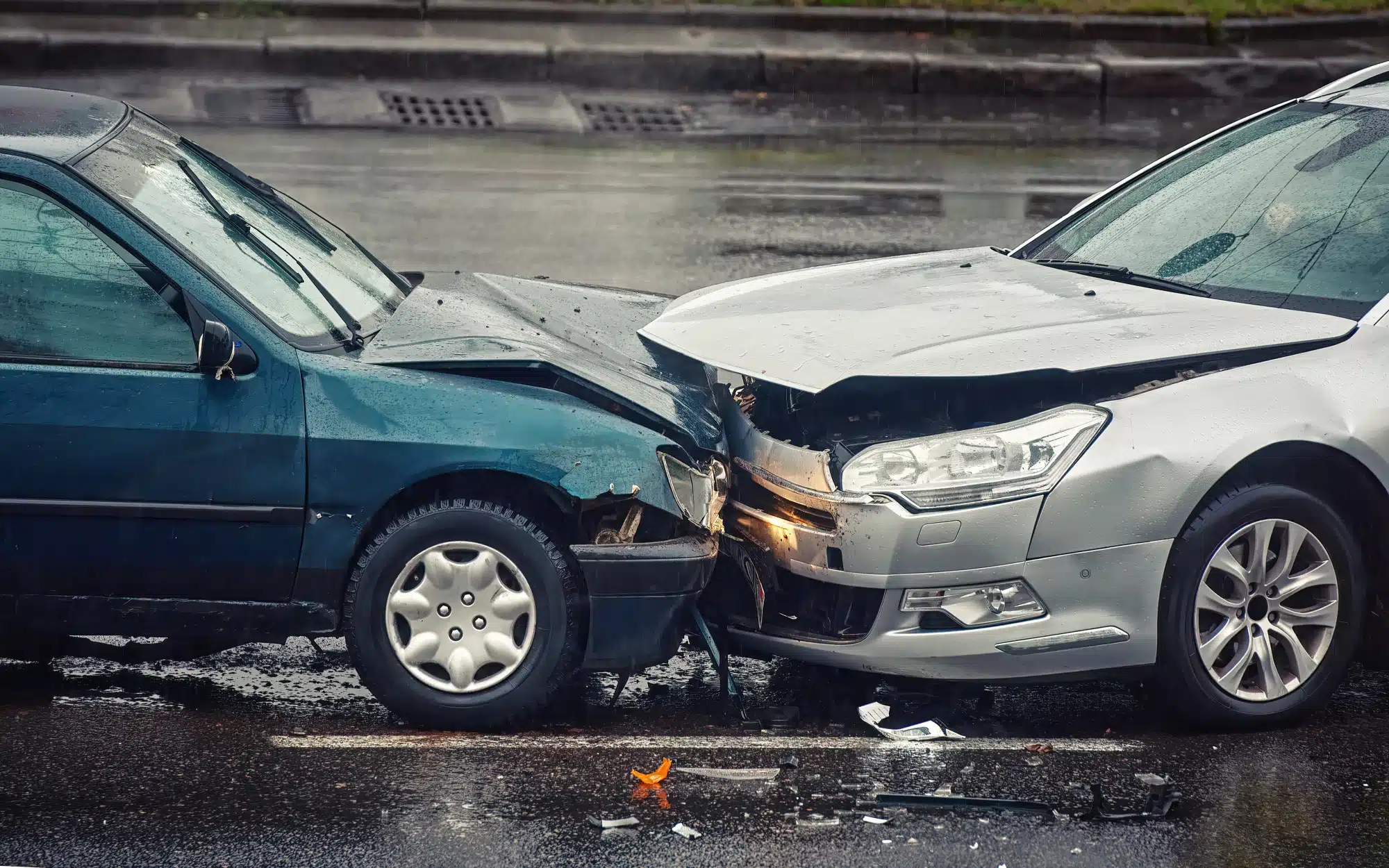 Two cars involved in a head-on collision on a rainy street.