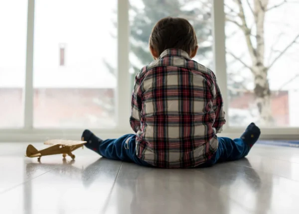 Sad child sitting on the floor alone, not being taken care of at daycare.