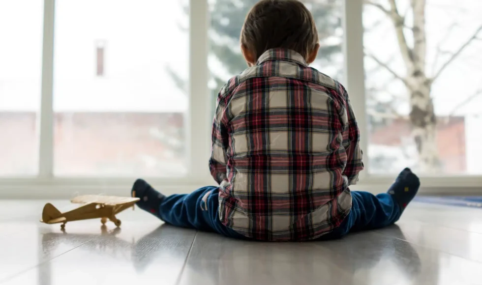 Sad child sitting on the floor alone, not being taken care of at daycare.