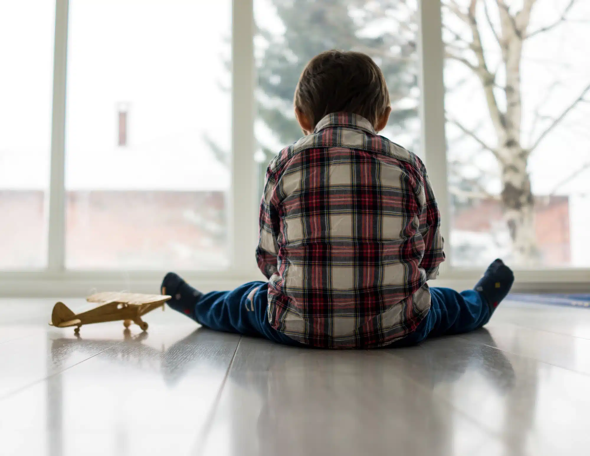 Sad child sitting on the floor alone, not being taken care of at daycare.