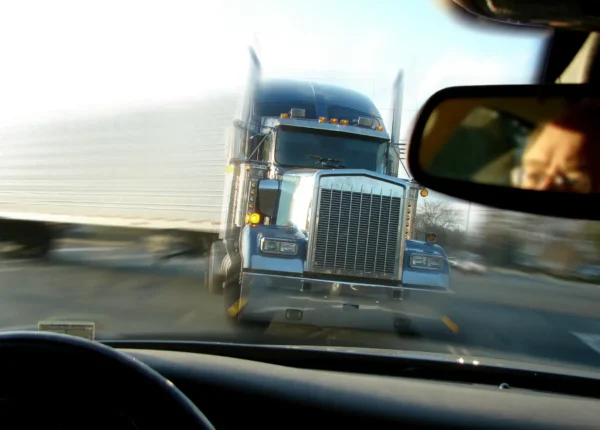 View over a car’s dashboard of an oncoming semi-truck.