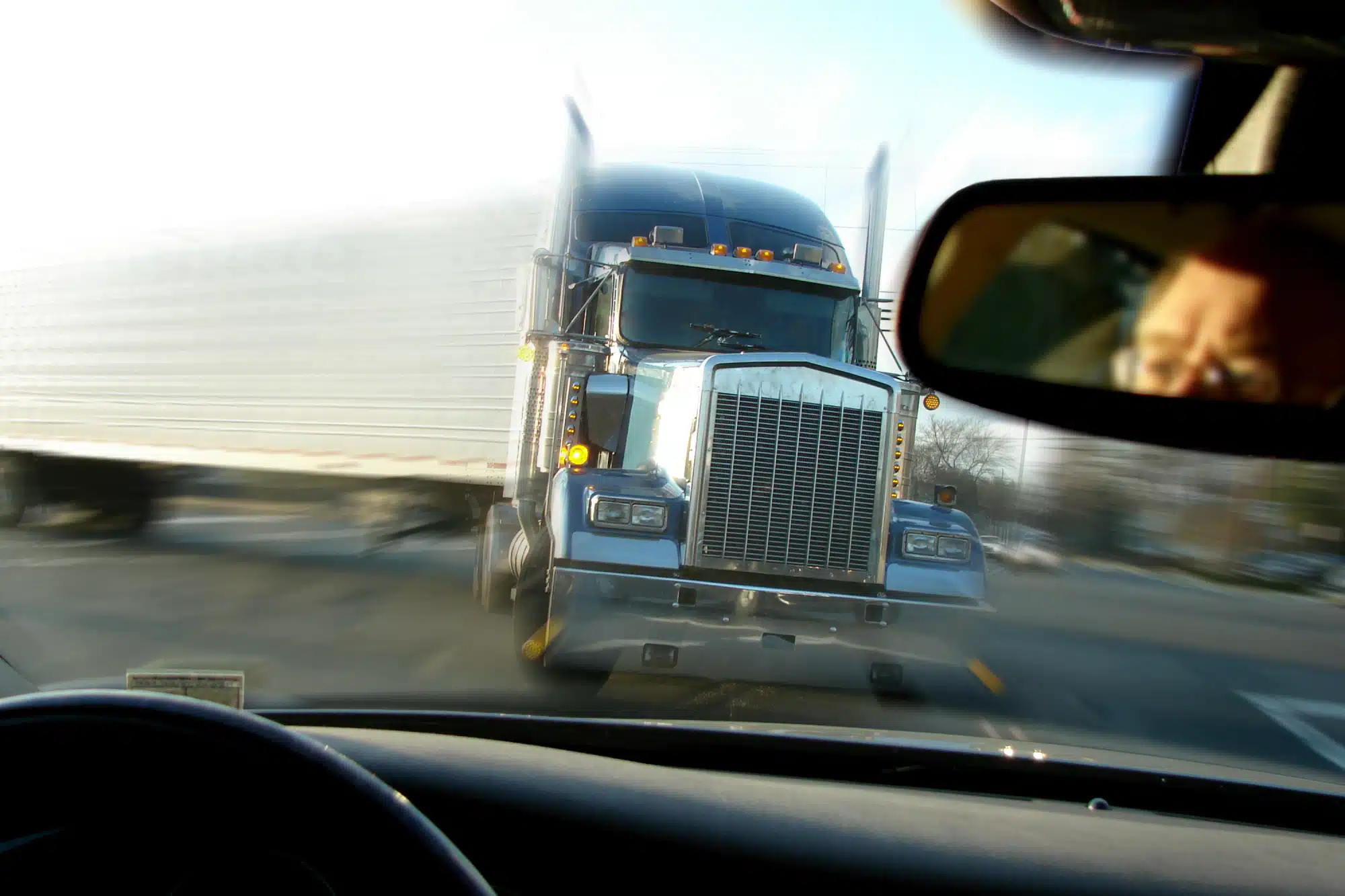 View over a car’s dashboard of an oncoming semi-truck.