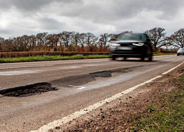 Blurred car approaching a deep, unmarked pothole