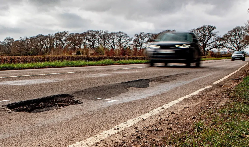 Blurred car approaching a deep, unmarked pothole