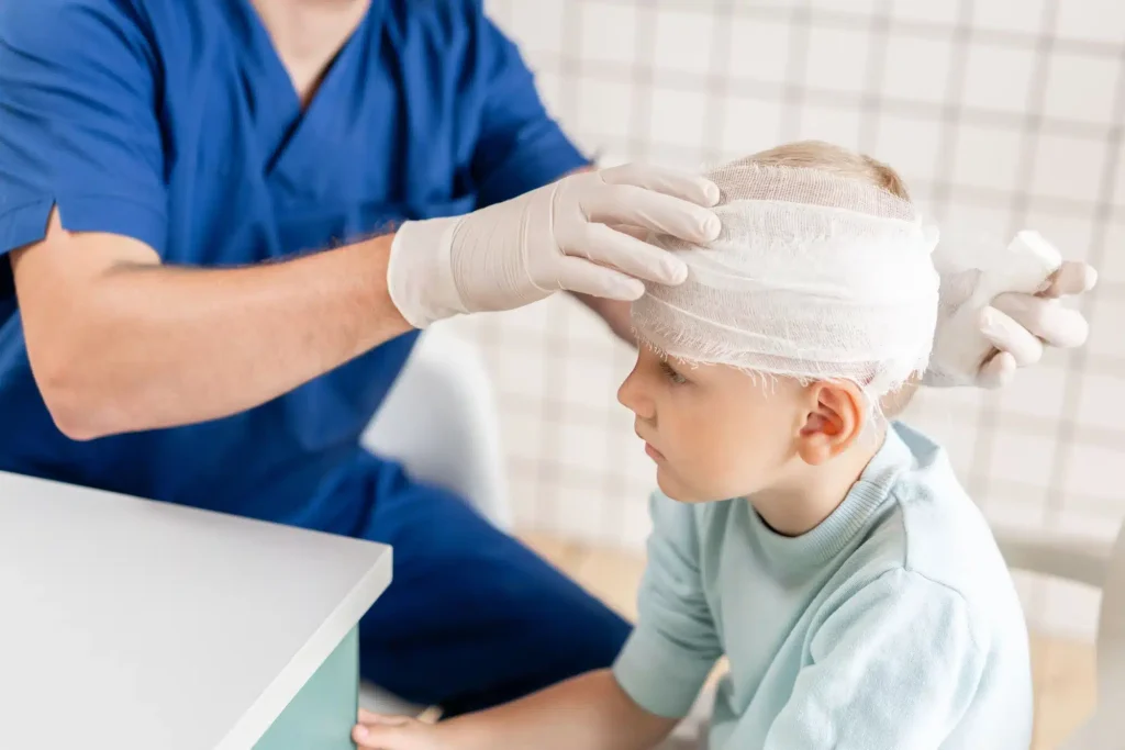 Young boy getting his head injury wrapped by a doctor