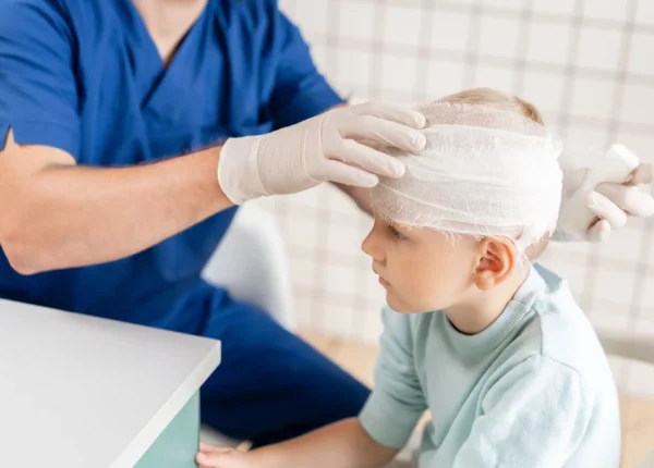 Young boy getting his head injury wrapped by a doctor