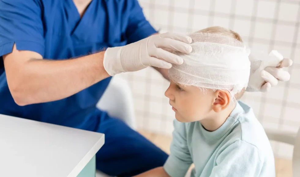 Young boy getting his head injury wrapped by a doctor