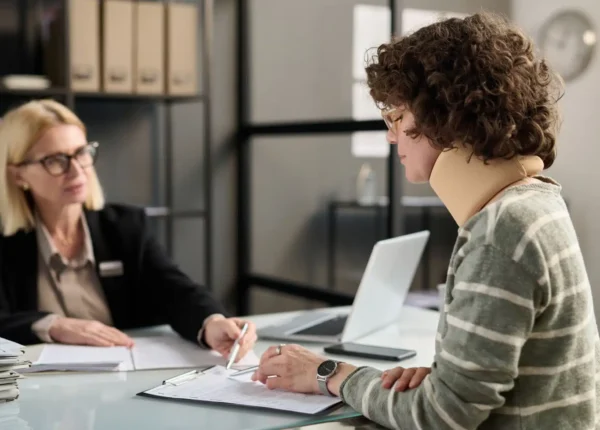 Young woman in a neck brace filing documents