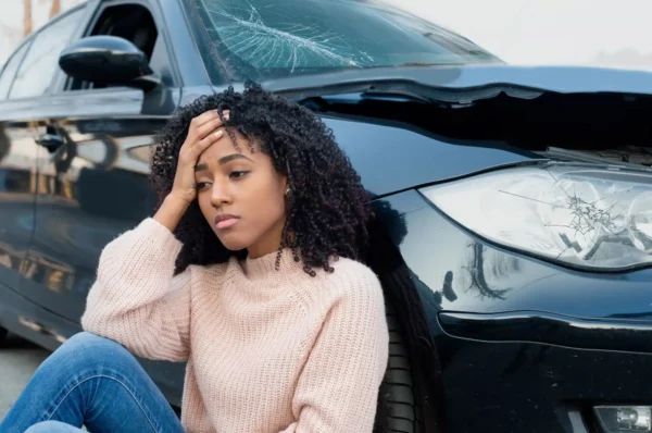 Distressed woman slumped next to her crashed car