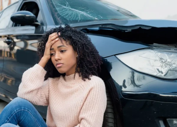 Distressed woman slumped next to her crashed car