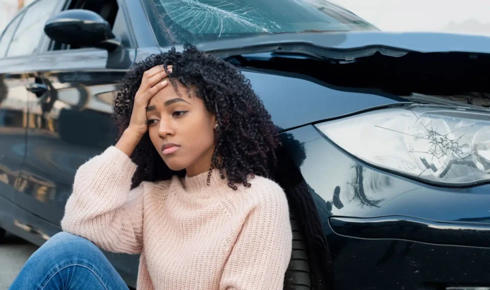 Distressed woman slumped next to her crashed car